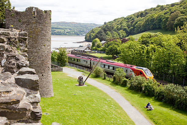 virgin lentes voyager tren que pasa castillo de conwy - conwy castle train travel people traveling fotografías e imágenes de stock