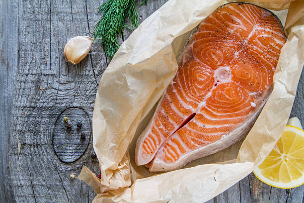 istock Salmon steak with lemon slice, herbs, pepper, garlic 471557000