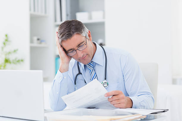 istock Tensed male doctor reading document in clinic 471557336
