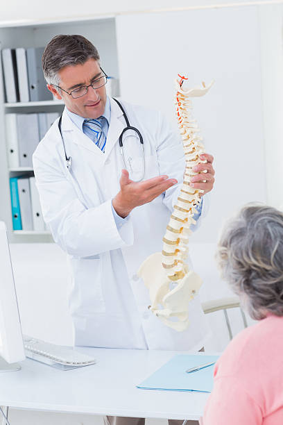 istock Doctor explaning anatomical spine to female patient 471557544