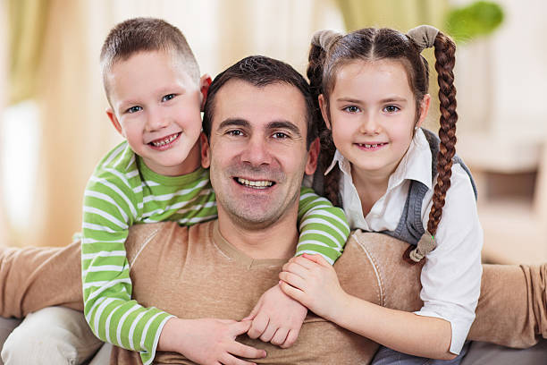 istock Smiling children embracing their father and looking at camera. 471558452