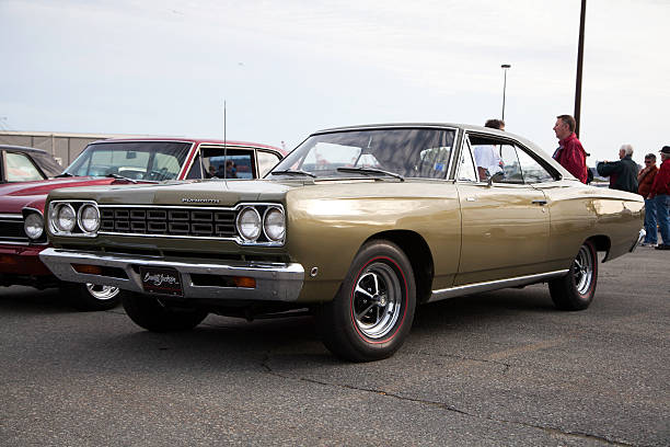 Dartmouth, Nova Scotia, Canada - June 6, 2013: At a public car gathering, a Plymouth Roadrunner parked in a parking lot.  In frame, other cars are visible around Plymouth.  In addition some people are visible in background admiring the many vehicles.