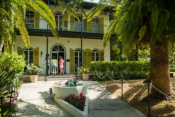 Ernest Hemingway's memorial house  in Key West, Florida, USA Key West, USA - March 18, 2013: Ernest Hemingway's house  in Key West, Florida, USA. Tree tourists entering the home.. hemingway house stock pictures, royalty-free photos & images