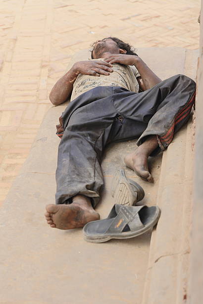 Bhaktapur, Nepal - October 5, 2012: Nepali workingman sleeps at noon -siesta- after having worked the whole morning on October 5, 2012 in the Durbar Square of Bhaktapur-Kathmandu Valley-Nepal.