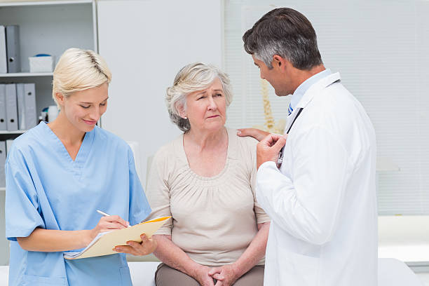 istock Doctor consoling patient while nurse writing reports 471559316