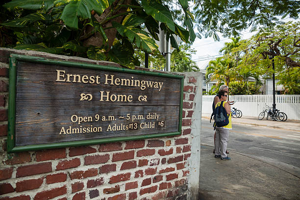 Ernest Hemingway Home  in Key West, Florida, USA Key West, USA - March 18, 2013: Memorial plate on the garden's wall of the Ernest Hemingway house  in Key West, Florida. Two tourists, man and woman, looks the map next to the wall. hemingway house stock pictures, royalty-free photos & images