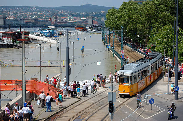 Budapest, Hungary - June 09, 2013: Flooded embankment of the Pest (east) side of town. Hordes of catastrophe tourists looking on. Tram service is still functioning.
