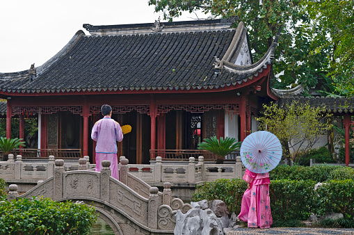 Suzhou, Jiangsu, China - October 25th, 2010: Man and woman in traditional clothes walking in Shanxi Guildhall Garden, near Pingjiang Road.
