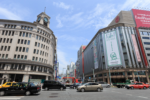 Tokyo, Japan - June 3, 2013 : Pedestrians and traffics move past Ginza street in downtown Tokyo. Ginza shopping district, the most expensive real estate price in Japan. The historic building is the landmark in Ginza - The Wako store. 