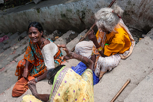 Varanasi, India - August 10, 2011: beggars seek alms on concrete steps leading to bank of river Ganges at Varanasi, Uttar Pradesh, India. This shot was taken near one of the ghats, holy bathing places, along the river.