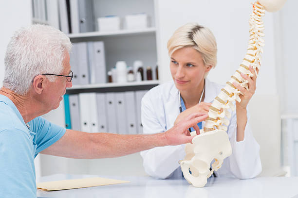 istock Senior patient showing spine problems to doctor at table 471561640