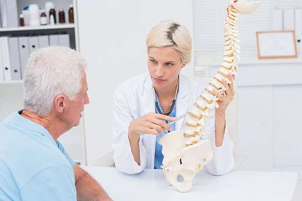 istock Doctor explaning spine model to senior patient 471561644