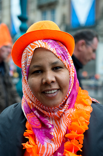 Amsterdam, the Netherlands - April 30th, 2013 : Young woman wearing an orange hat over her headscarf, joining the party during the coronation day of king Willem Alexander