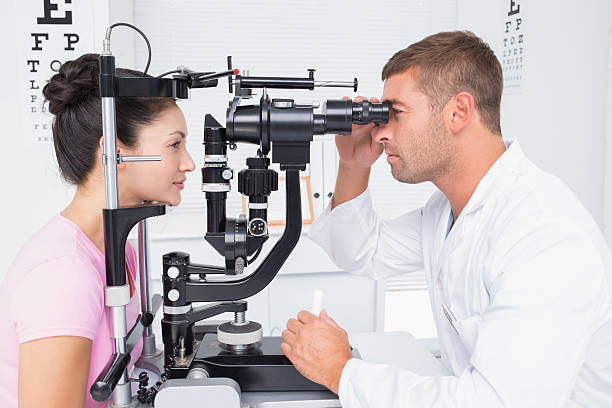 istock Optician examining womans eyes through slit lamp 471562744