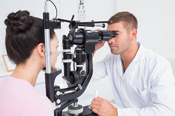 istock Optician examining female patients eyes through slit lamp 471562758
