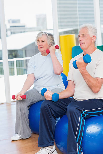 istock Senior couple lifting dumbbells on exercise ball 471563006
