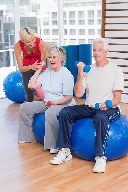 istock Trainer motivating senior couple in lifting dumbbells 471563044