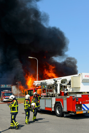 Kampen, The Netherlands - June 8, 2013: Fire fighters in front of a a fire engine trying to put out a fire in an industrial area in the town of Kampen in The Netherlands.