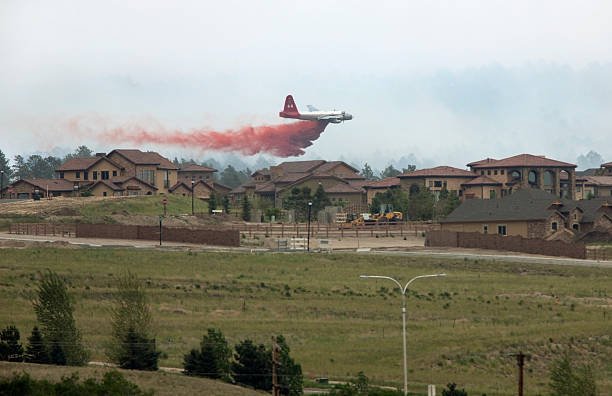 Lockheed aircraft drops fire retardant near Colorado Springs homes Colorado Springs, Colorado, U.S.A. - June 13, 2013:  With smoke and heat waves rising, a huge C-130 fire fighting aircraft drops red fire retardant near homes on the southern part of the Black Forest fire in Colorado Springs, Colorado's most destructive fire ever.  military tanker airplane photos stock pictures, royalty-free photos & images