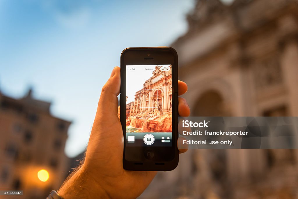 photographing the Trevi Fountain in rome Rome, Italy - June 12, 2013: : Man holding the new iPhone 5 and photographing the Trevi Fountain in Rome with his smartphone. The iphone 5 is the new smartphone made by Apple Inc. It was released on September 21st on US and in Uk on 2012, the iPhone 5 is Apple's first mobile phone with a 4" retina touch-screen and 8mpx camera. Night scene in rome Photography Stock Photo