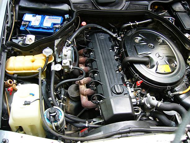 Focused automotive service technician inspecting bolts on cylinder head cover in garage
