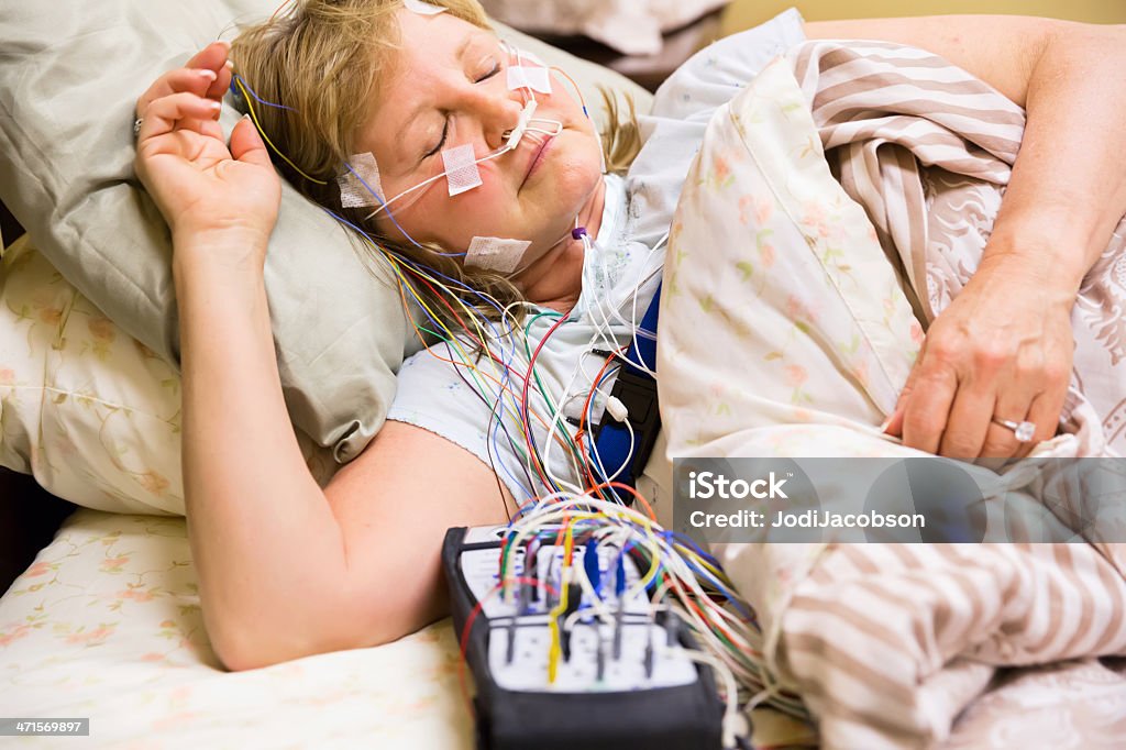 Woman wired for sleep study Woman sleeping in a bed in the hospital with equipment attached during a sleep study. RM.  rr Sleeping Stock Photo