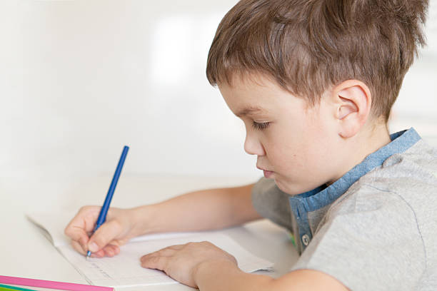 istock Serious pensive pupil sits at desk 471573444