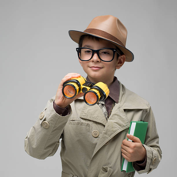 istock Little detective looking through hand held telescope on gray background 471574635