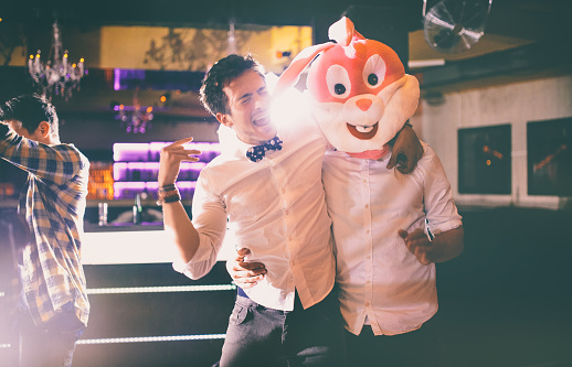 Guy standing next to a friend wearing a bunny head, singing along to the music in a night club