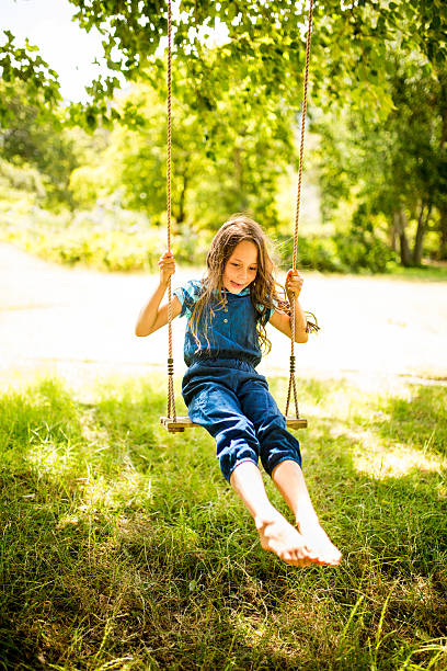 istock Happy girl having fun swinging and feeling the grass 471576484