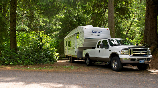 Newport, Oregon, USA - June 12, 2013: A Campsite in Beverly Beach State Park. A Komfort brand Fifth Wheel Travel Trailer and Ford F350 Pickup are shown pulling out of the camping space.