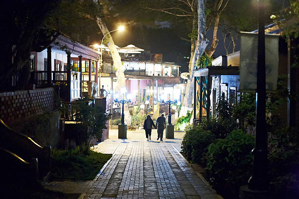 Lima, Peru - May 19, 2013: Mature couple at night walking hand in hand on an illuminated pedestrianised street in the Barranco area of Lima city