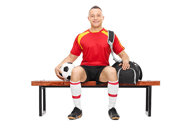 istock Young guy holding football seated on a bench 471577296