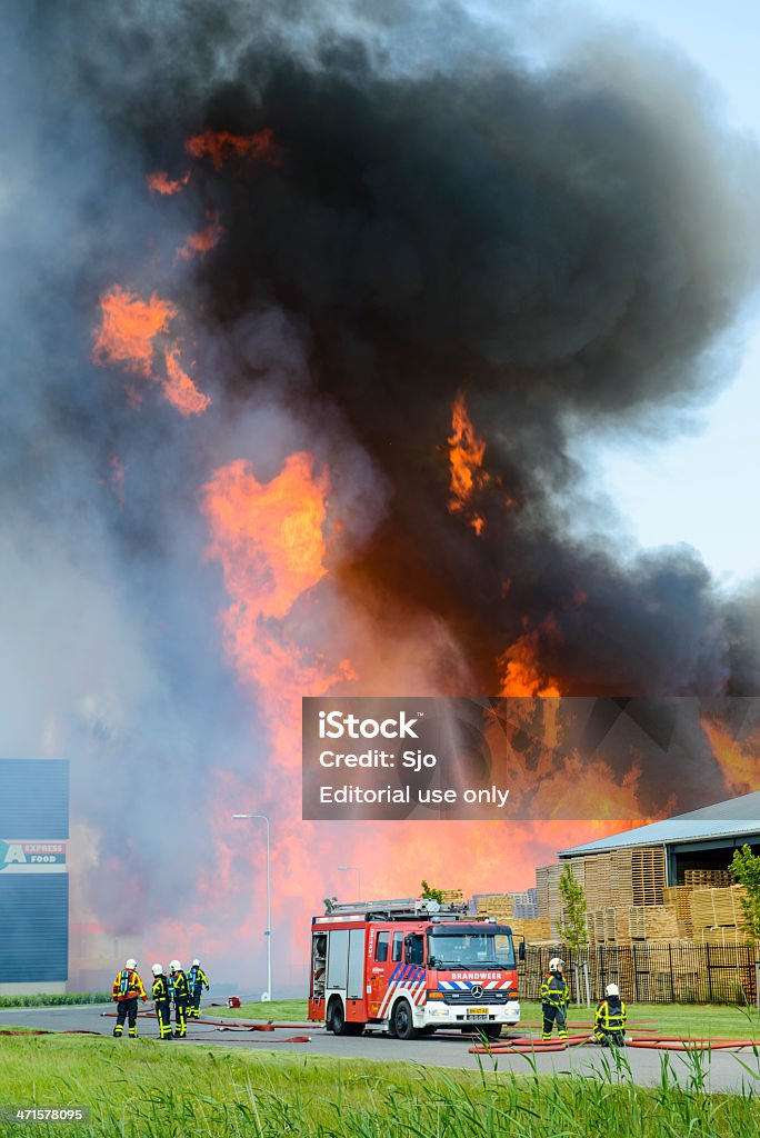 Fire fighting Kampen, The Netherlands - June 8, 2013: Fire fighters trying to put out a fire in an industrial area in the town of Kampen in The Netherlands. Building Exterior Stock Photo