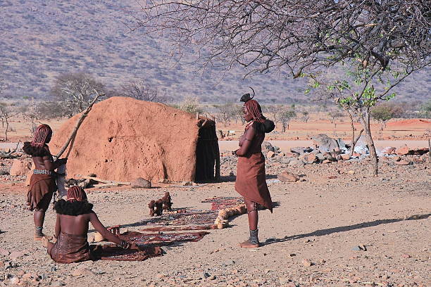 Epupa, Kaokoland, Namibia - October 16, 20210: Three young himba women prepare their handicrafts on the ground to sell them to the tourists on October 16, 2010 in a hamlet near Epupa falls-Kunene región-Kaokoland-Namibia.