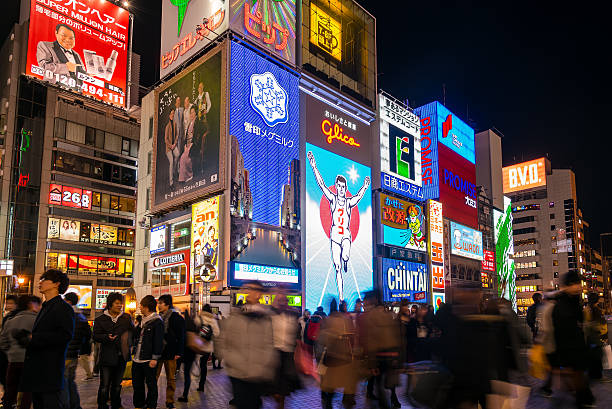 Osaka, Japan- March 2, 2015 : Unidentify tourists take a photo with the Glico Man, light billboard in Dotonbori shopping street in Osaka, Japan