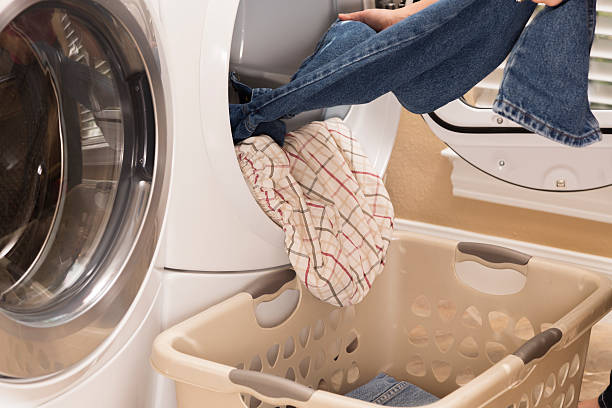 Domestic Life:  House wife removing clothes from dryer.  Laundry basket Domestic Life:  House wife removing towels from clothes dryer to Laundry basket tumble dryer stock pictures, royalty-free photos & images