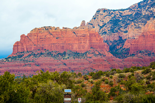 Spectacular red colored rock formations in Sedona, Arizona under cloudy sky. The red rocks form a popular backdrop for many activities, such as spiritual pursuits, hiking and mountain biking along hundreds of trails.  There is green vegetation living on the rocks surface.  Shot with a Canon 5D mark 3.  rm