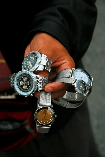 Shanghai, China - October 28, 2007: A Chinese salesman shows his merchandise of fake designer watches on the Bund in Shangha. There are some 30 to 40 million counterfeit watches put into circulation each year, 40% of which are manufactured in China.