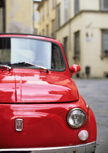 Lucca, Italy - March 23, 2013: a traditionally Italian, classic Fiat 500 car, old style, is parked in an as well old district (the city centre) of the Tuscan town.