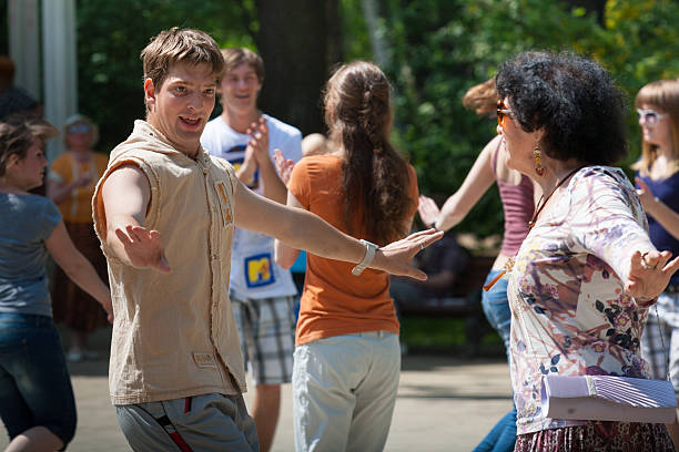 Moscow, Russia - May 18, 2012: Company of strangers dance in the local public park at a weekly held dance party, cheerful and happy men and women show their best dancing moves while being relaxed and having fun. People use mostly Russian folk choreography