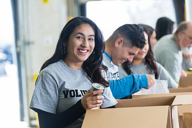hispanic female добровольцев сортировка пожертвования в продуктовый банк - food canned food drive motivation стоковые фото и изображения