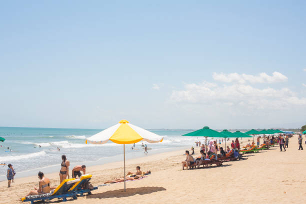 Tourists on Kuta Beach Bali Indonesia Kuta, Indonesia - September 25, 2014: Groups of tourists enjoying the tropical sunshine on Kuta Beach, Bali, Indonesia kuta beach stock pictures, royalty-free photos & images