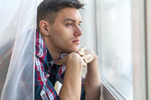 istock Handsome pensive man guy watching through the window concept sadness 471588562