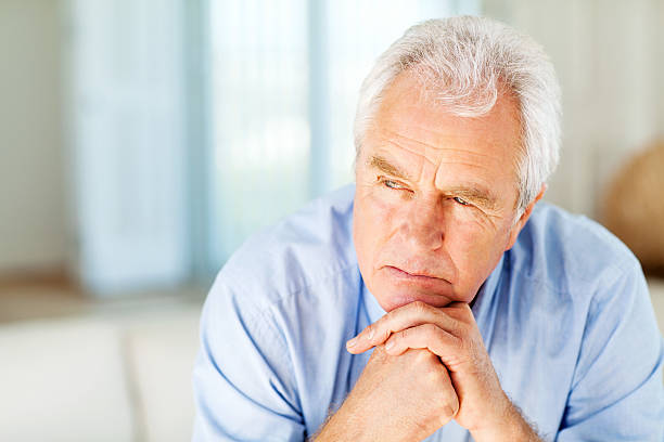 istock Senior Man With Hand On Chin Looking Away At Home 471588749