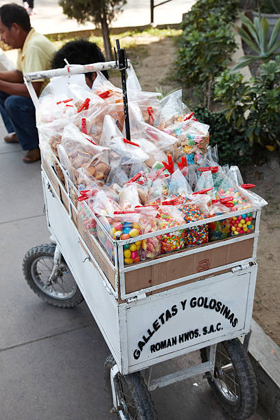 Ica, Peru - May 21, 2013: Candy seller with street cart on the streets of Ica in Peru. Two men are pictured sitting on the kerb