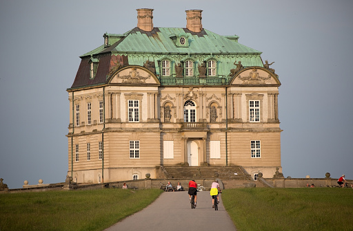 Lyngby, Denmark - June 20, 2013:People enjoying the late evening nordic sun the day before summer solstice in front of the newly restored  Eremitage Castle in Dyrehaven - the Deer park - north of Copenhagen.