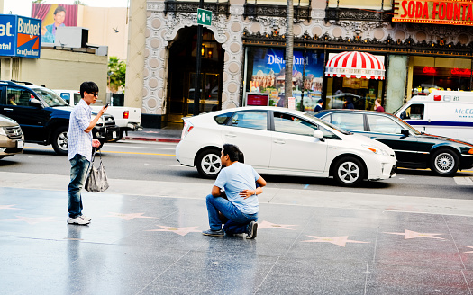 Hollywood, USA - May 7, 2013: Asian tourists on Hollywood Boulevard, visiting Walk Of Fame, photographing each other with star shaped celebrities names