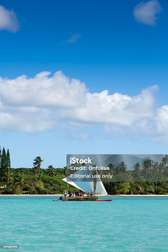 Tourist Group on Dugout Canoe, Isle of Pines, New Caledonia Pines Island, New caledonia - January 19, 2013: Tourists enjoying a tour on a Pirogue on crystal clear water in a bay of Pines Island, New Caledonia. New Caledonia Stock Photo