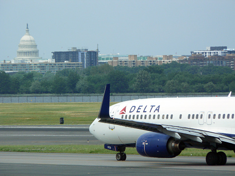 Washington, DC, USA - June 2, 2013: Delta Airlines jet taxiing in front of the US Capital at Ronald Reagan Washington National Airport (IATA: DCA). The airport is located just across the Potomac River from the National Mall, with convenient public transportation to downtown business and government districts.